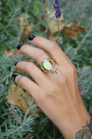 Hand-modeled image of Galaxy III signet ring with bright rainbow colored opal on a finger to show its size and how it looks when worn.