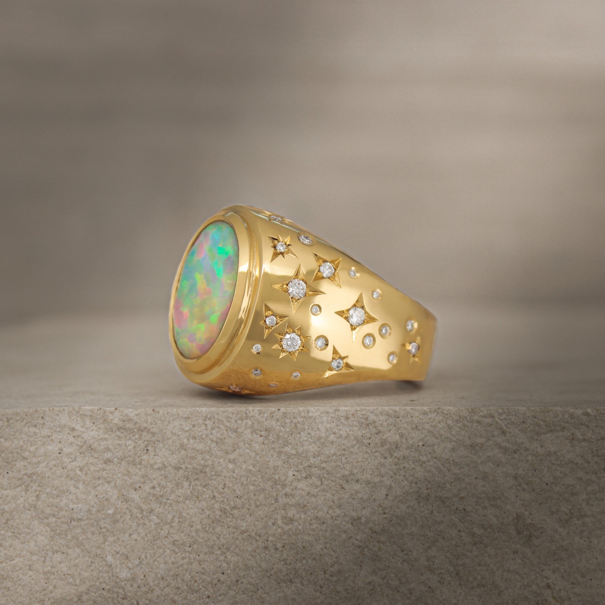 Close-up view of Galaxy III signet ring with 4ct opal and diamond accents on 18k yellow gold band.