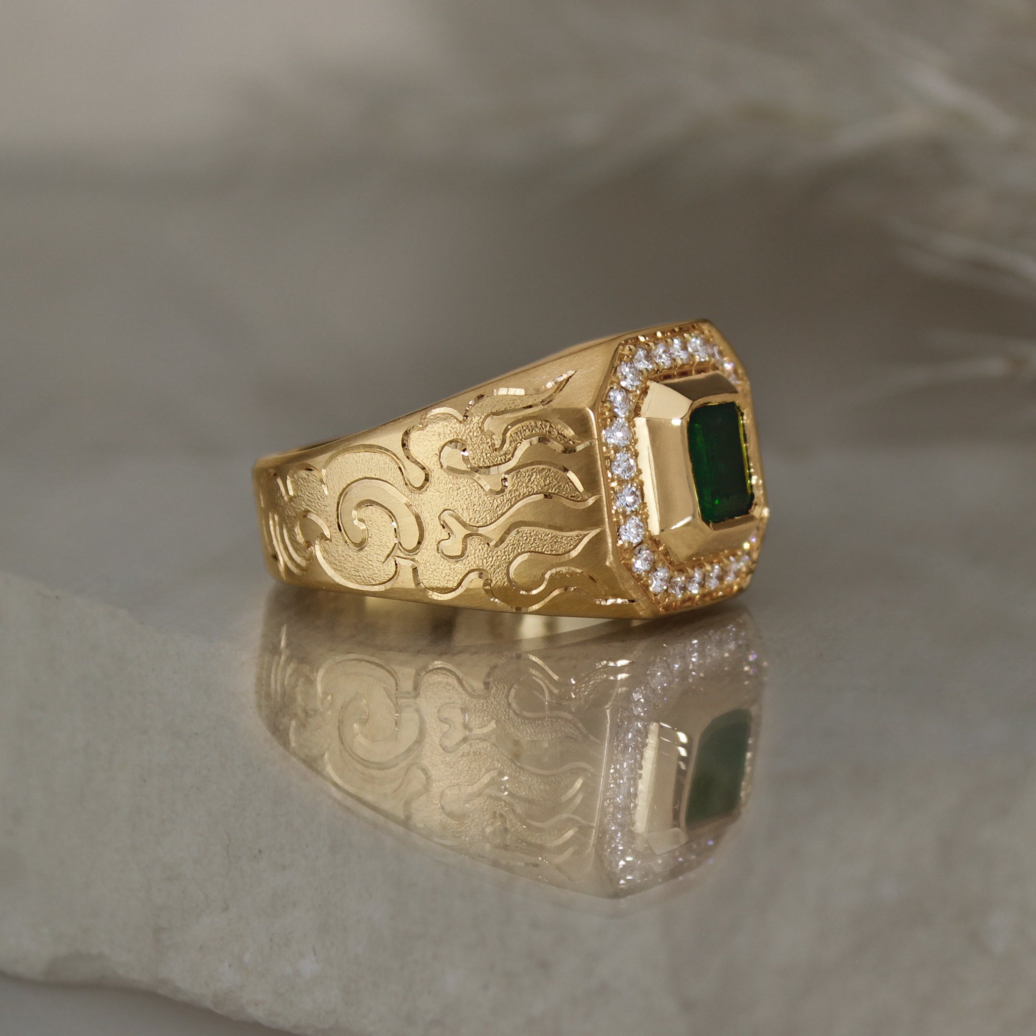 signet style 14k yellow gold ring with a green tourmaline square shape bezel set followed by a diamond halo with cut corners, engraved with fire on the side