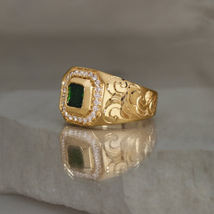 signet style 14k yellow gold ring with a green tourmaline square shape bezel set followed by a diamond halo with cut corners, engraved with water waves on the side