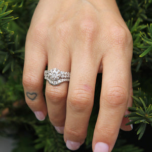female model hands wearing a breathtaking wedding set featuring a prong-set round diamond in the engagement ring and accent diamonds throughout both ring