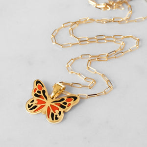 Side view of 18k yellow gold butterfly pendant with delicate wings and intricate details.