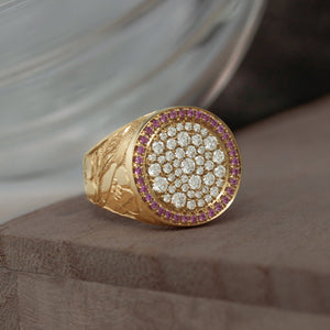 Close-up shot of the face of the ring, showing the intricate floral and leaf engravings on the band and the sparkling diamonds and pink sapphires on the face.